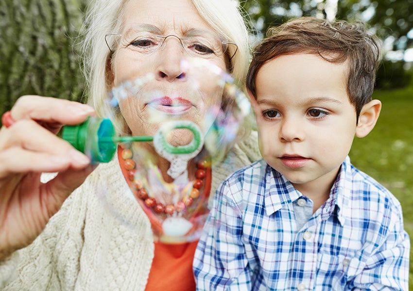 Grandmother blowing bubbles with grandson